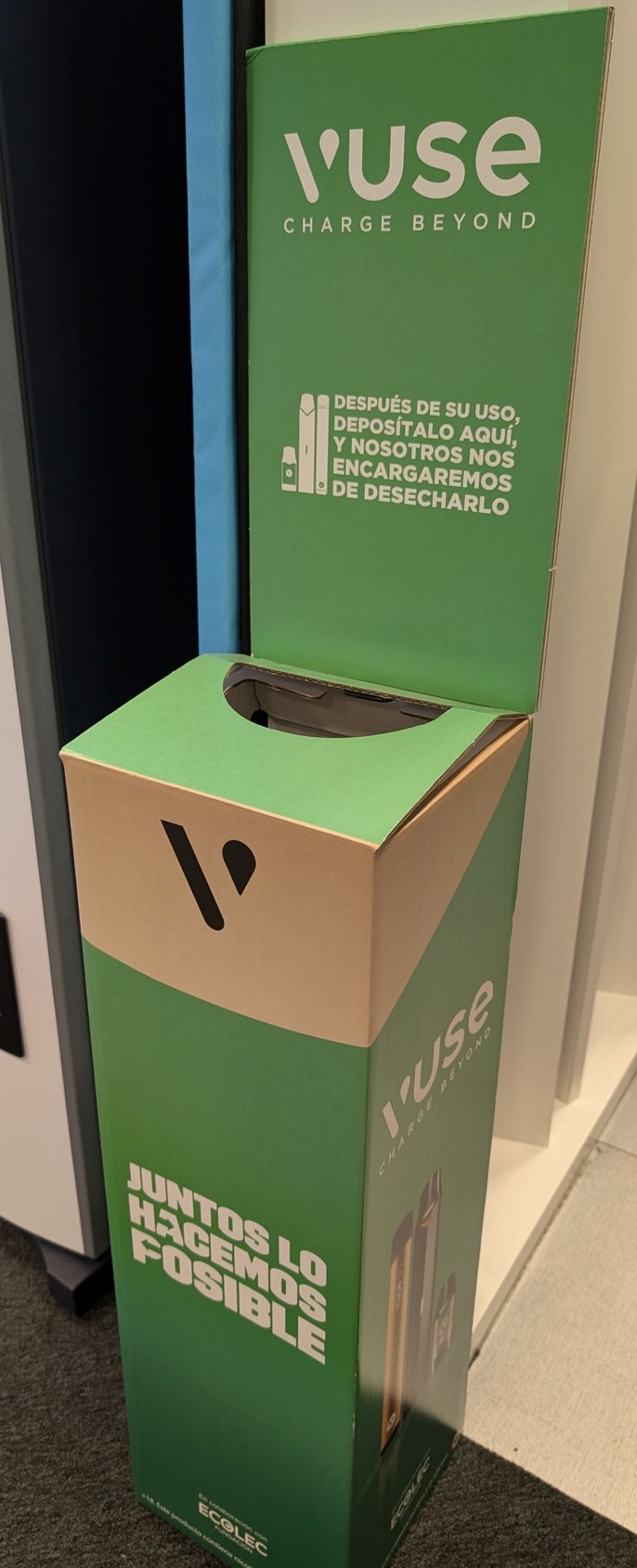 Contenedor verde de reciclaje para productos Vuse, con tapa abierta y mensajes que indican depositar dispositivos usados para su desecho responsable. Incluye logos de Vuse y Ecogec, y la frase ‘Juntos lo hacemos posible’.