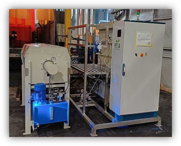 Equipo industrial con un módulo de control y una unidad hidráulica conectada, instalado en una planta de producción.