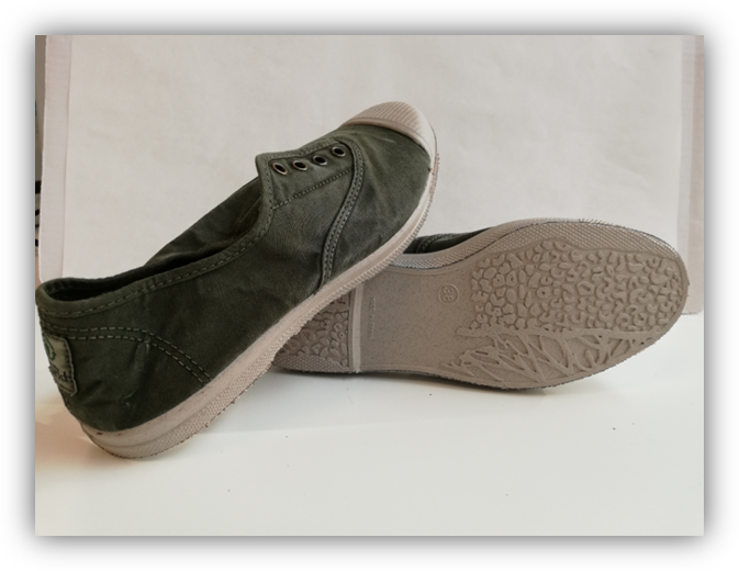 Un par de zapatillas de lona verde, una apoyada sobre la otra mostrando la suela texturizada.