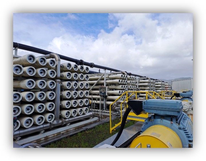 Instalación industrial con módulos de filtración de membranas, tuberías y equipos mecánicos al aire libre bajo un cielo nublado.