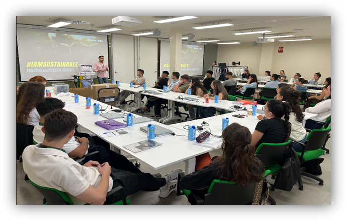 Personas participan en una sesión formativa sobre sostenibilidad en un aula con mesas y una presentación proyectada
