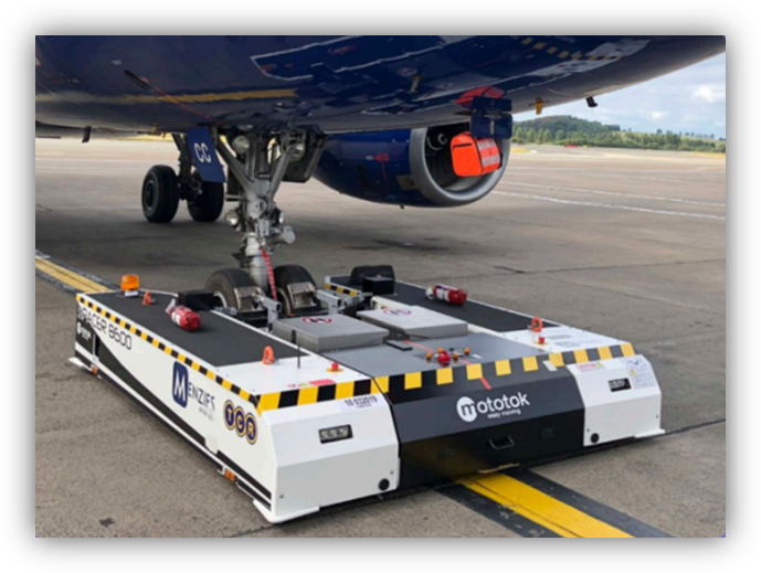 Equipo de remolque eléctrico conectado al tren de aterrizaje de un avión en pista de aeropuerto