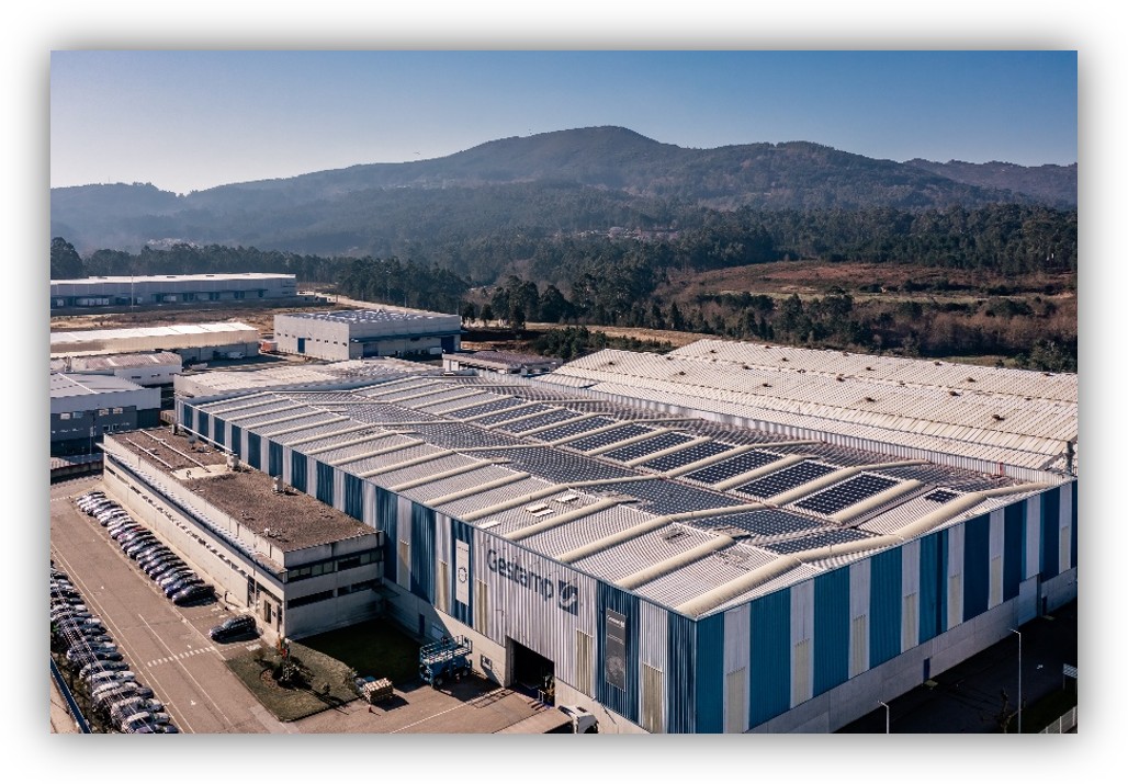 Vista aérea de una planta industrial de Gestamp con paneles solares instalados en la cubierta, rodeada de zonas industriales y montañas