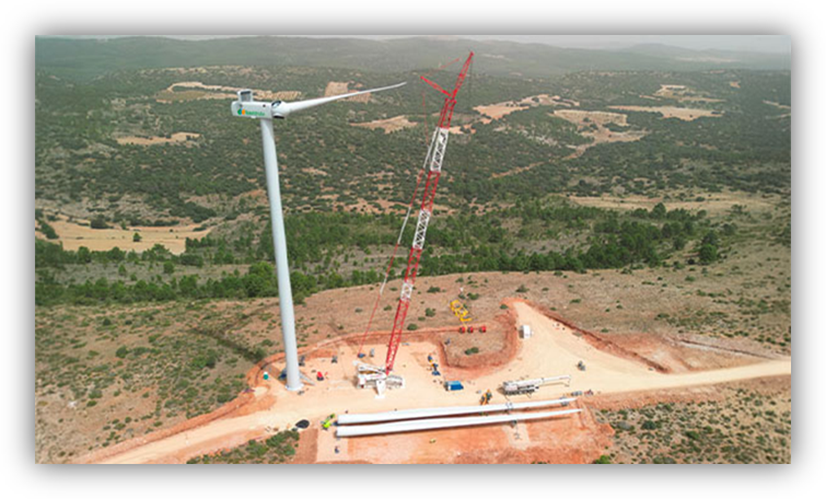 Aerogenerador en proceso de instalación en un parque eólico, con una gran grúa trabajando en un entorno rural.