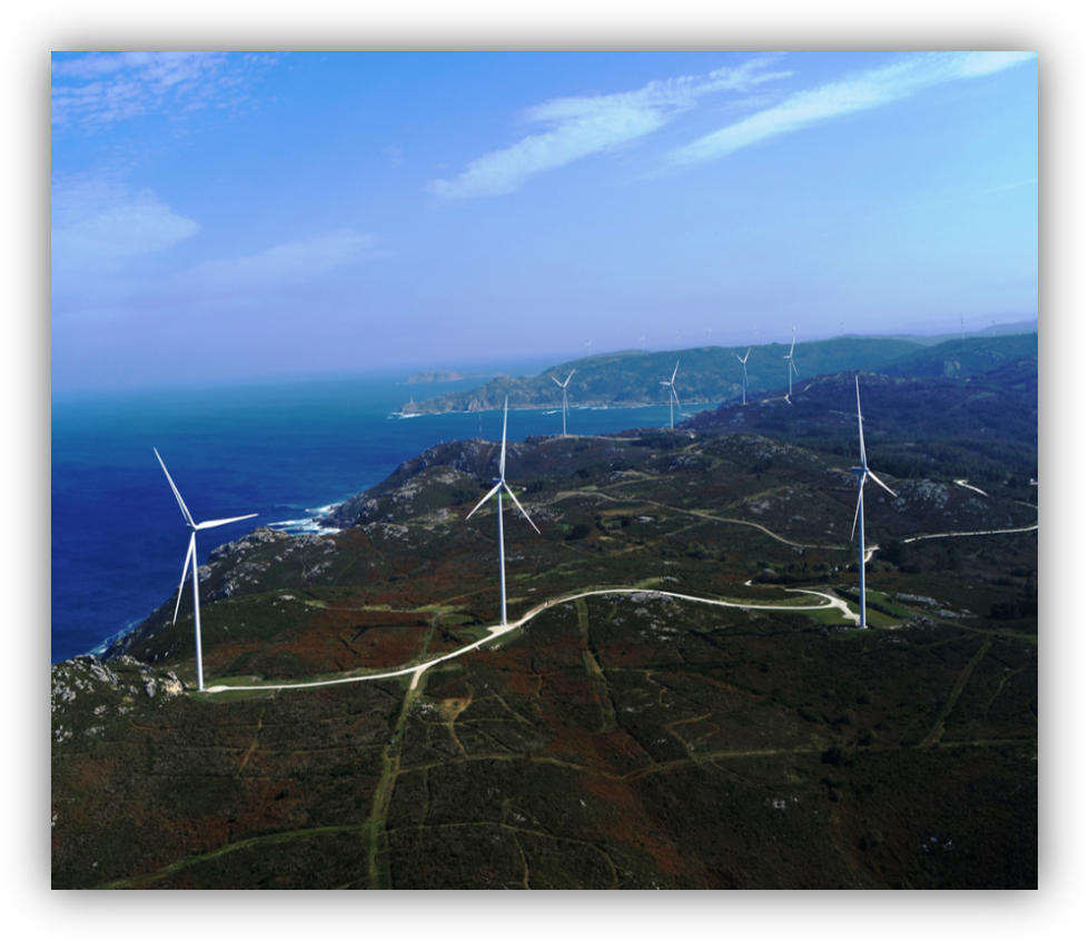 Vista aérea de varios aerogeneradores instalados en una zona costera con el mar al fondo.