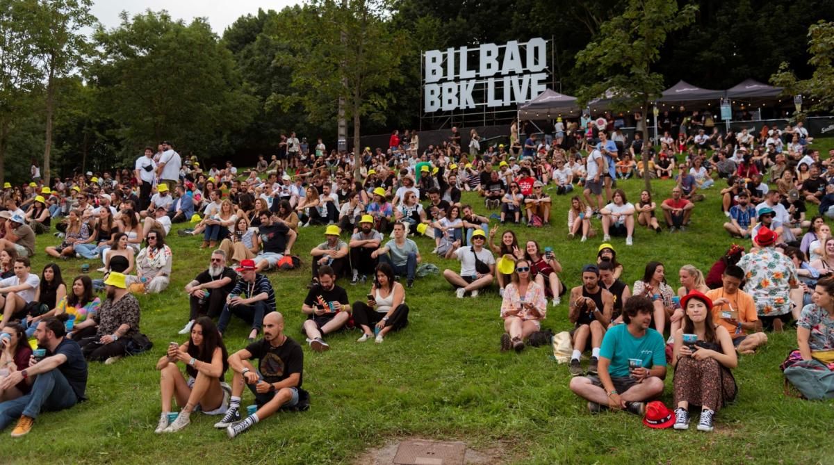 Grupo de personas en una colina durante el festival Bilbao BBK LIVE, con un bosque al fondo.