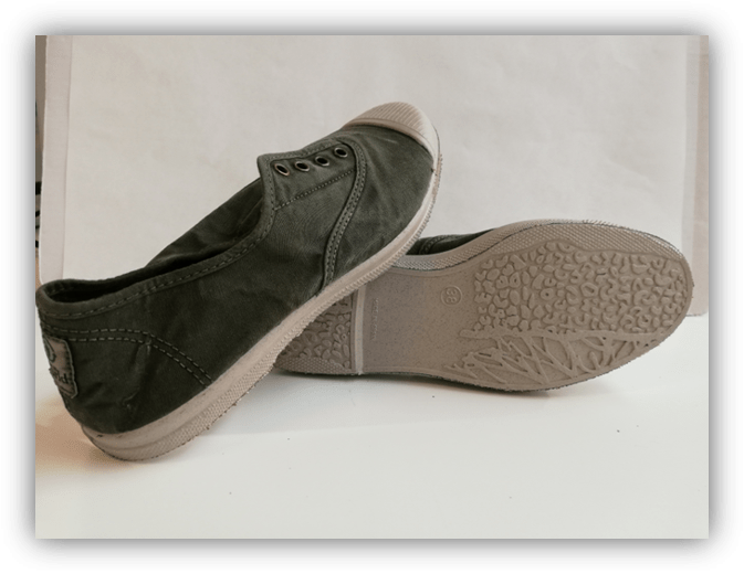 Un par de zapatillas de lona verde, una apoyada sobre la otra mostrando la suela texturizada.