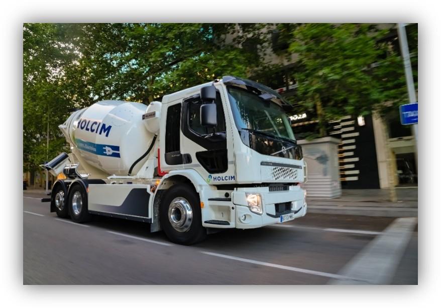 Camión hormigonera de Holcim circulando por una calle con árboles