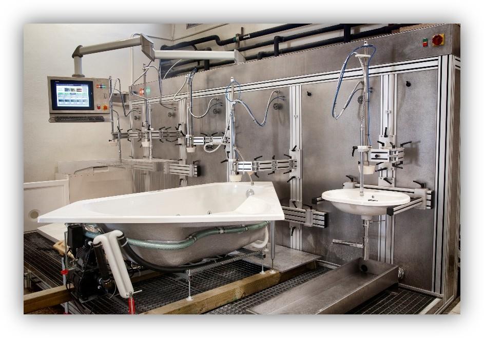 Instalación industrial de pruebas con una bañera y un lavabo conectados a equipos y tuberías.