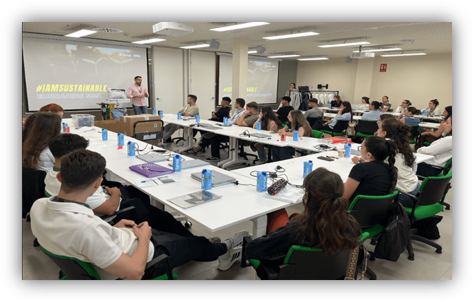 Personas participan en una sesión formativa sobre sostenibilidad en un aula con mesas y una presentación proyectada