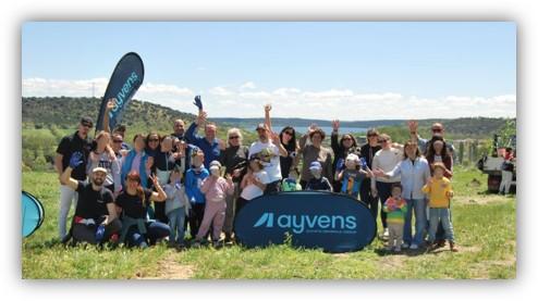 Grupo de personas reunidas al aire libre posando juntas en una actividad de voluntariado, con una pancarta de Ayvens.