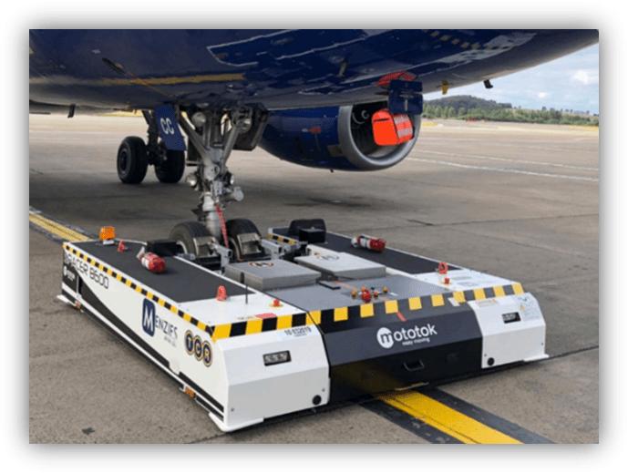 Equipo de remolque eléctrico conectado al tren de aterrizaje de un avión en pista de aeropuerto