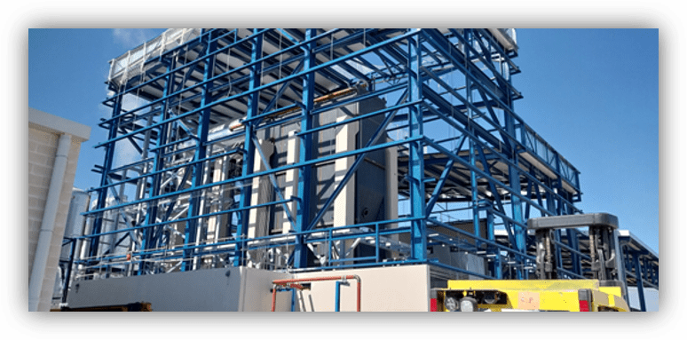 Estructura industrial con armazón metálico azul que sostiene equipos y tuberías en una planta al aire libre.