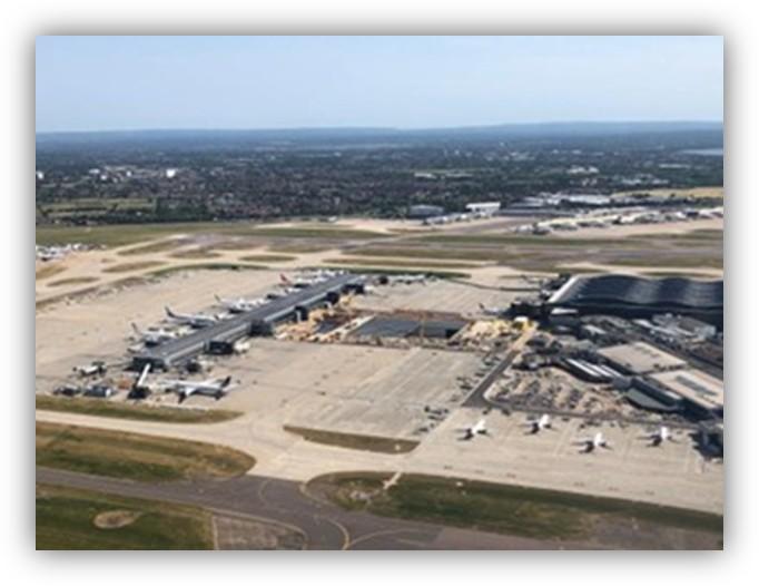 Vista aérea de un aeropuerto con varias pistas, terminales y aviones estacionados en la plataforma.