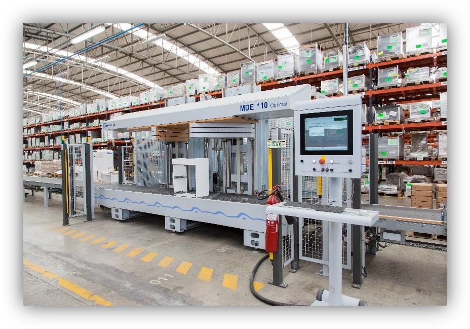 Máquina industrial automatizada en un almacén con estanterías llenas de cajas organizadas.