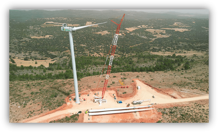 Aerogenerador en proceso de instalación en un parque eólico, con una gran grúa trabajando en un entorno rural.