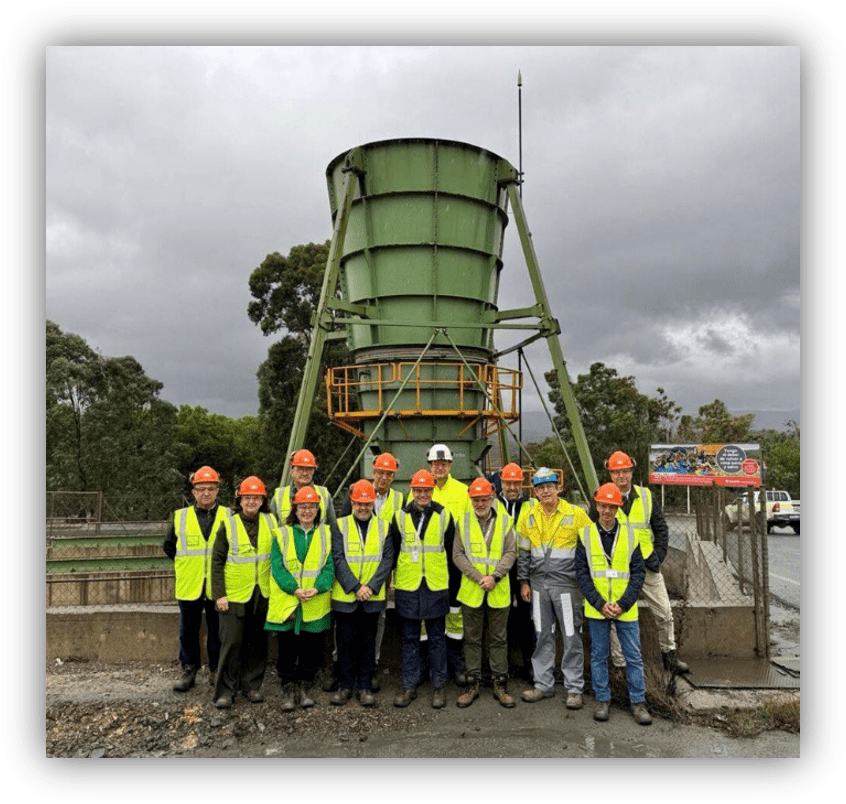 Grupo de personas con equipos de protección individual frente a una instalación industrial de tratamiento de agua.