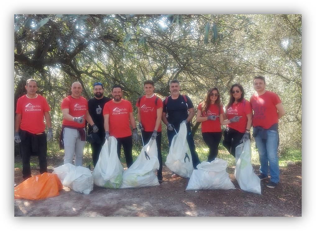 Grupo de personas participando en una jornada de limpieza de residuos en un entorno natural, con bolsas de basura recogidas.