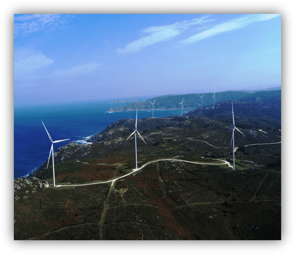 Vista aérea de varios aerogeneradores instalados en una zona costera con el mar al fondo.