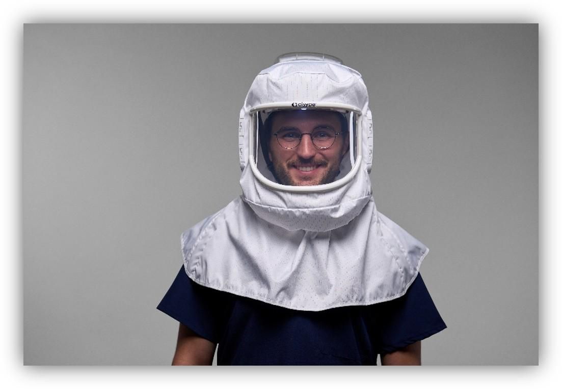 Persona con un equipo de protección respiratoria de color blanco que cubre la cabeza y el cuello, sobre fondo neutro.