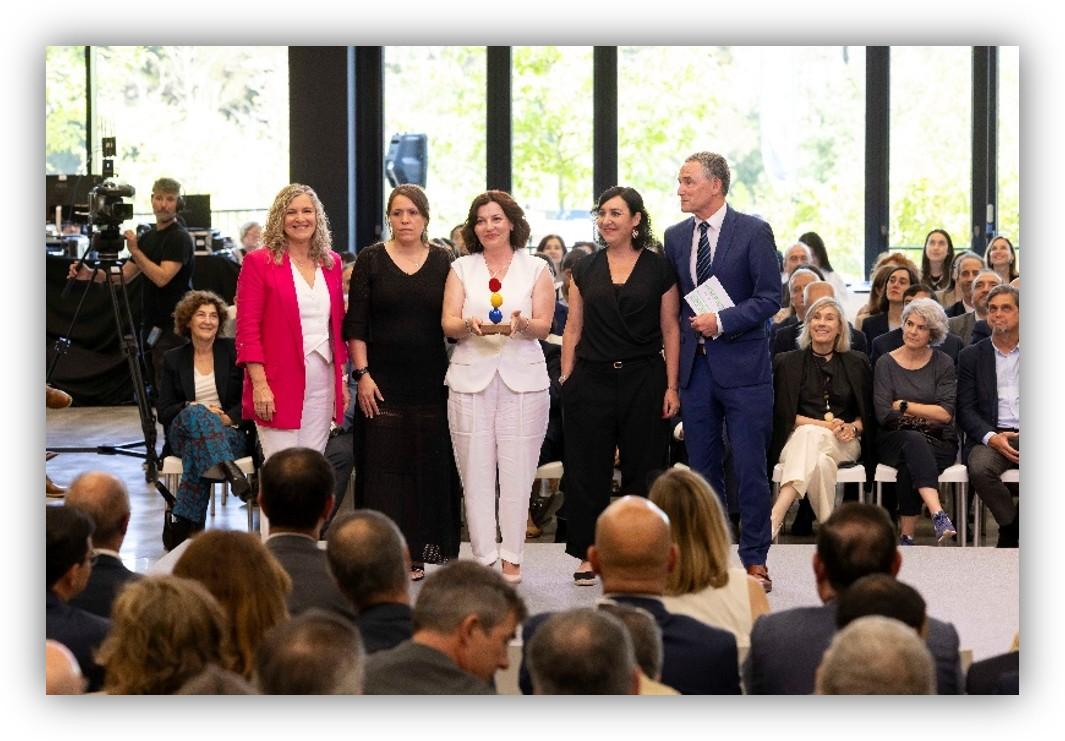 Grupo de personas sobre un escenario durante un acto de entrega de reconocimientos, ante una audiencia reunida en un auditorio.