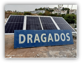 Panel informativo con el nombre Dragados situado frente a una instalación de paneles solares fotovoltaicos sobre una cubierta.