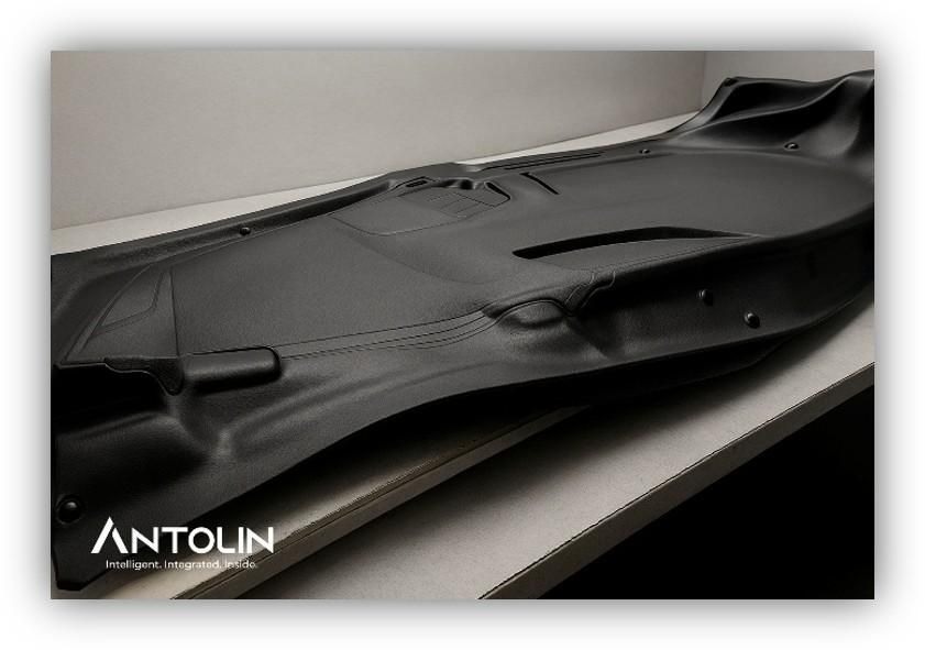 Componente interior de vehículo fabricado por Antolin, colocado sobre una mesa y diseñado con materiales sostenibles para la industria de la automoción.