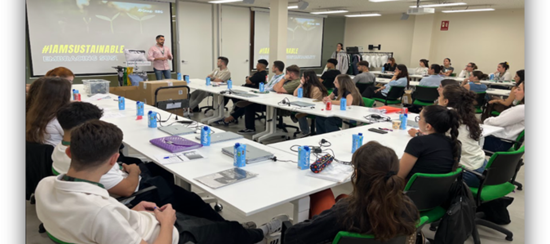 Personas participan en una sesión formativa sobre sostenibilidad en un aula con mesas y una presentación proyectada