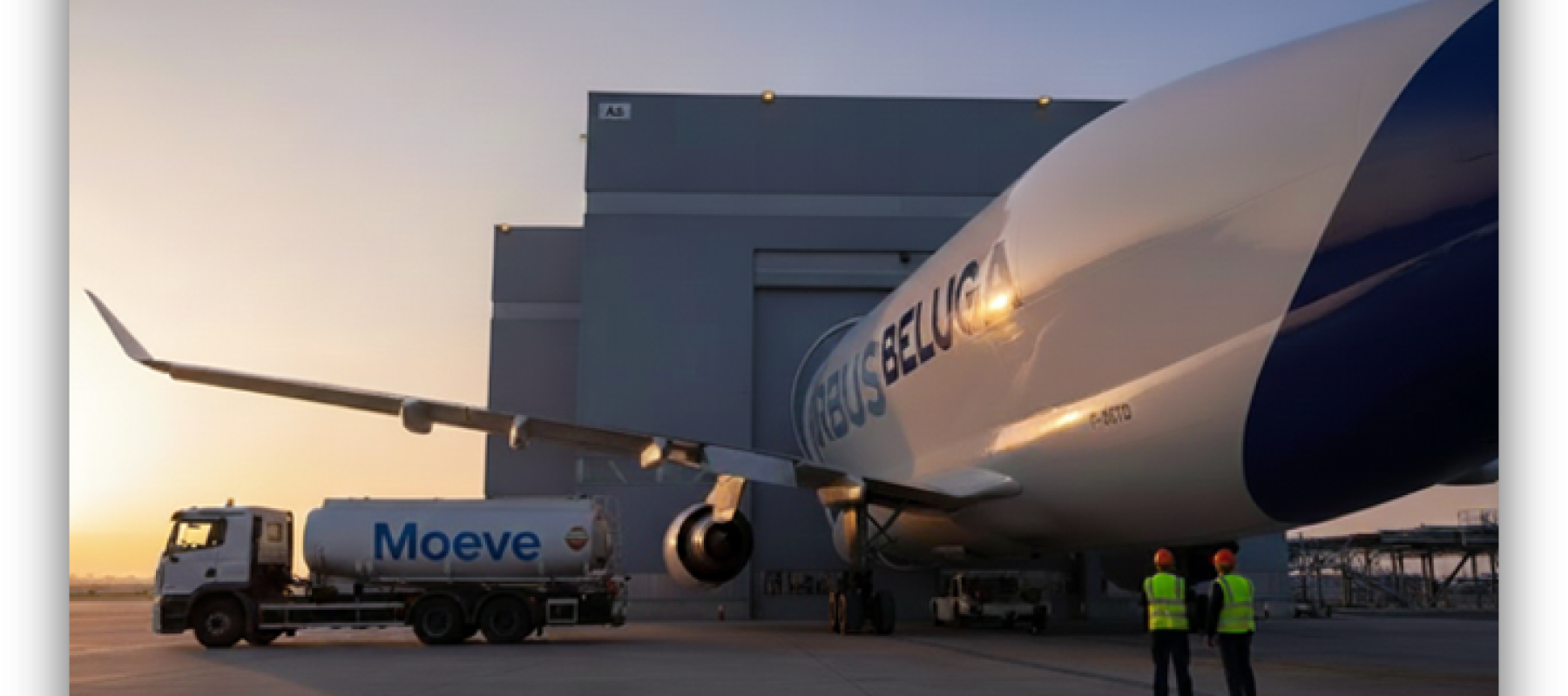 Avión Airbus Beluga estacionado junto a un camión cisterna de Moeve en una plataforma aeroportuaria, con personal y un hangar al fondo durante el atardecer.