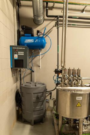 Instalación industrial para recirculación de agua de rechazo del proceso de ósmosis. Incluye compresor azul ABAC, secador Atlas Copco, depósito gris para almacenamiento y tanque metálico con válvulas y tuberías, utilizado para reutilizar hasta 600 m³ de agua en riego y sanitarios