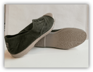 Un par de zapatillas de lona verde, una apoyada sobre la otra mostrando la suela texturizada.