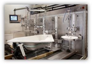 Instalación industrial de pruebas con una bañera y un lavabo conectados a equipos y tuberías.