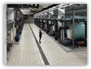 Técnica revisando una instalación industrial de tratamiento de agua con tuberías y equipos.
