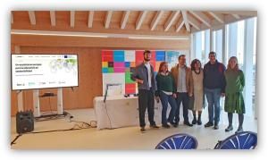 Grupo de personas posando en un evento sobre sostenibilidad en una sala con presentación y materiales informativos.