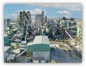 Planta industrial con estructuras metálicas, tuberías, silos y cintas transportadoras en un entorno abierto.