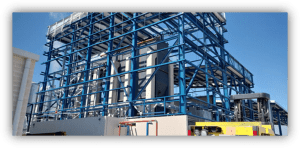 Estructura industrial con armazón metálico azul que sostiene equipos y tuberías en una planta al aire libre.