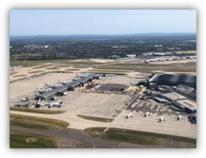 Vista aérea de un aeropuerto con varias pistas, terminales y aviones estacionados en la plataforma.