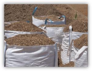 Sacos grandes llenos de material orgánico triturado, como restos vegetales o compost, almacenados en un terreno