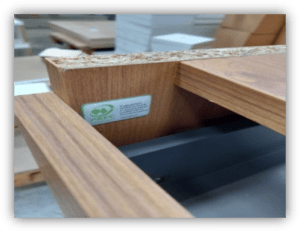 Detalle de una estructura de madera con tablero aglomerado y etiqueta de certificación forestal sostenible.