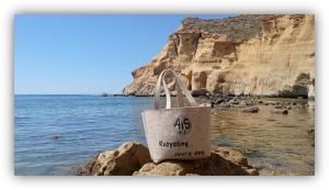 Bolsa reutilizable con el mensaje ‘Recycling every day’ colocada sobre unas rocas junto al mar, con acantilados al fondo.