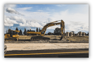 Excavadora trabajando en una obra de movimiento de tierras junto a una carretera, en un terreno abierto.