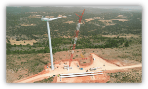 Aerogenerador en proceso de instalación en un parque eólico, con una gran grúa trabajando en un entorno rural.
