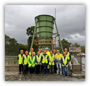 Grupo de personas con equipos de protección individual frente a una instalación industrial de tratamiento de agua.