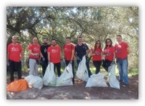 Grupo de personas participando en una jornada de limpieza de residuos en un entorno natural, con bolsas de basura recogidas.