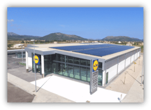 Supermercado Lidl con paneles solares instalados en la cubierta del edificio y montañas al fondo.